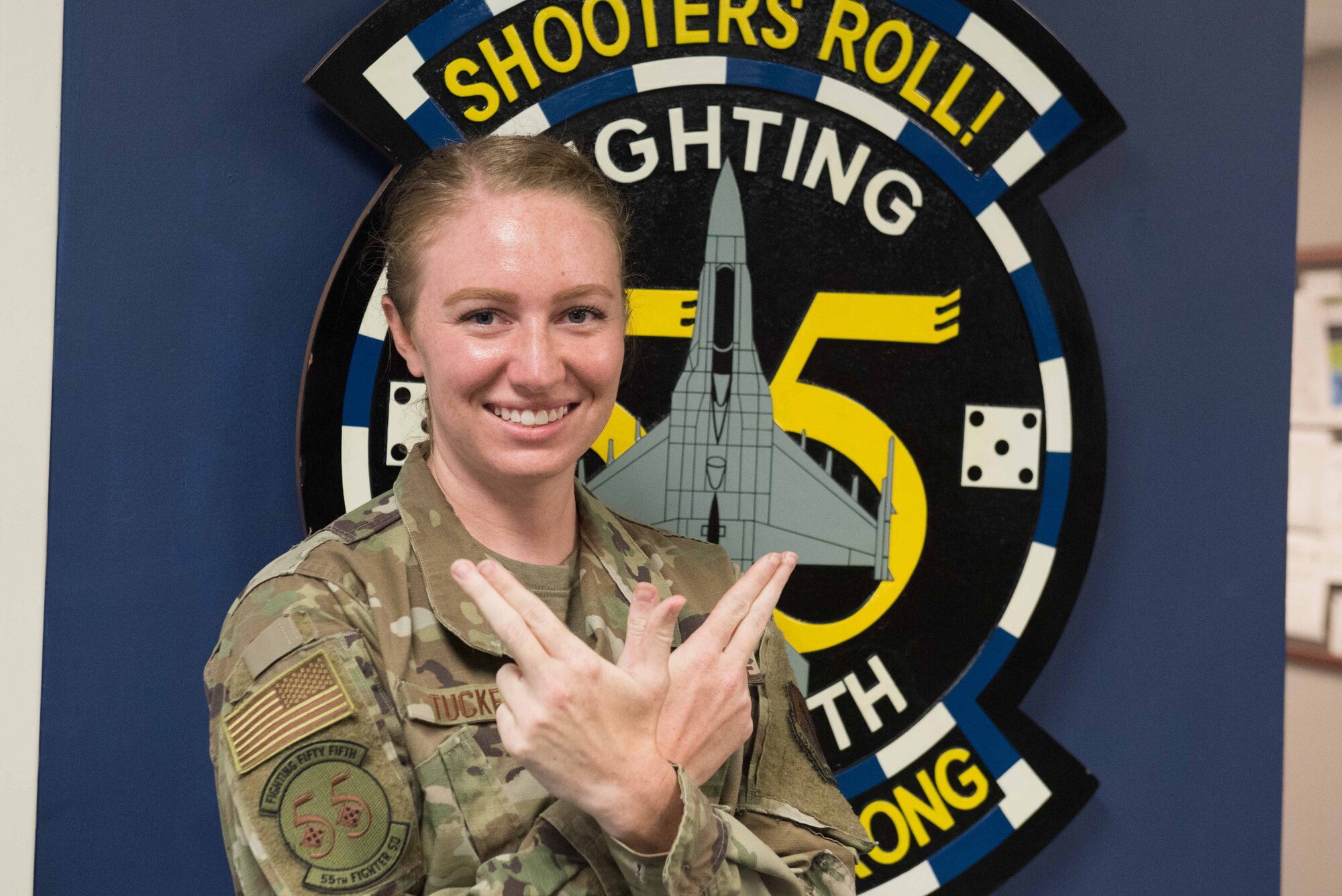 Image of a 55th Fighter Squadron Airman displaying their squadron hand signal.