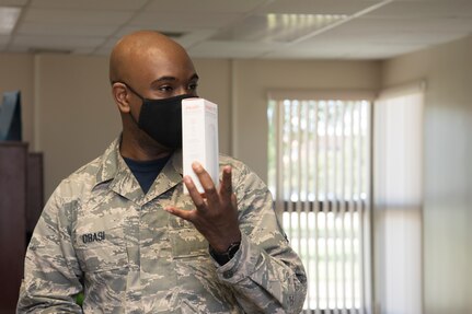An Airman holds up a box to others