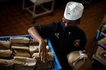 U.S. Marine Corps Lance Cpl. Lynne Ngogwet, a food service specialist with Base Food Service, Marine Corps Installations Pacific, loads meals onto a cart on Camp Kinser, Okinawa, Japan, July 13, 2020. MCIPAC base food services has created a full-time team of Marines that have prepared more than 30,000 boxed meals for ROM Marines across the entire island. Thousands more boxed meals are expected to be prepared in the coming weeks. (U.S. Marine Corps photo by Lance Cpl. Isaac Munce)