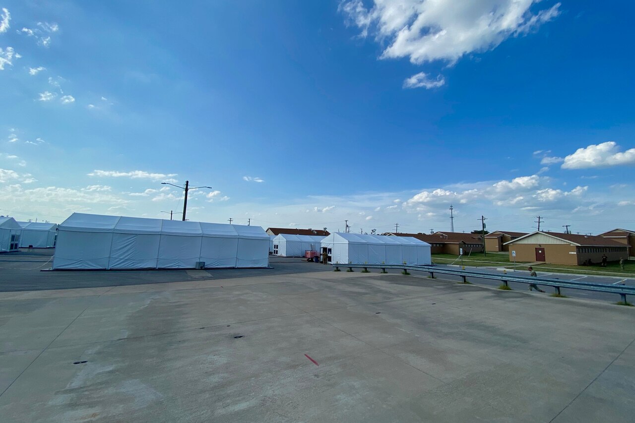 A parking lot is dotted with several white tents.