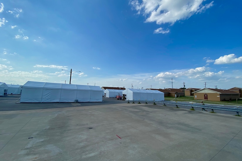 A parking lot is dotted with several white tents.