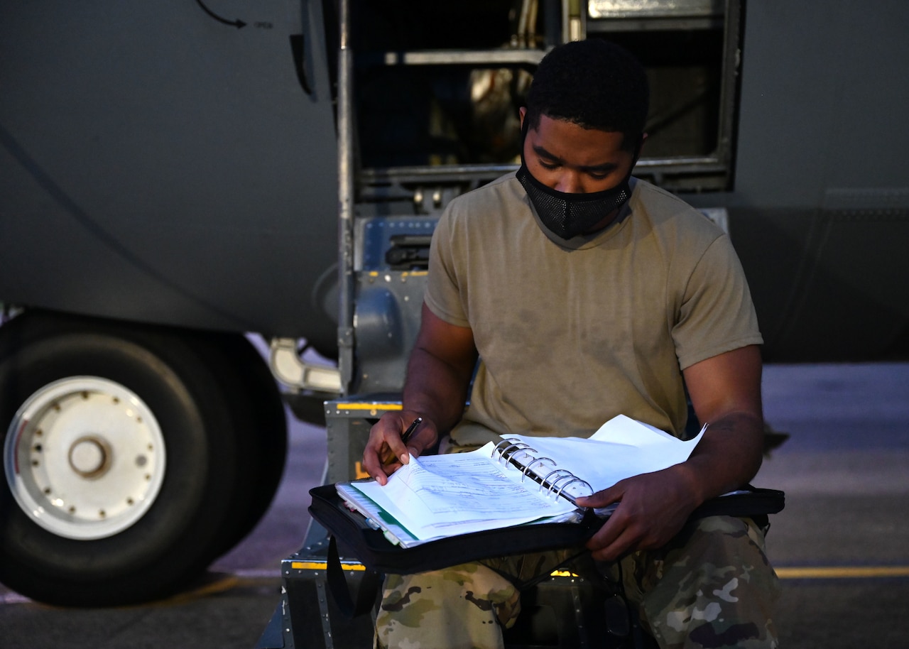 An Air Force crew chief flips through a notebook.