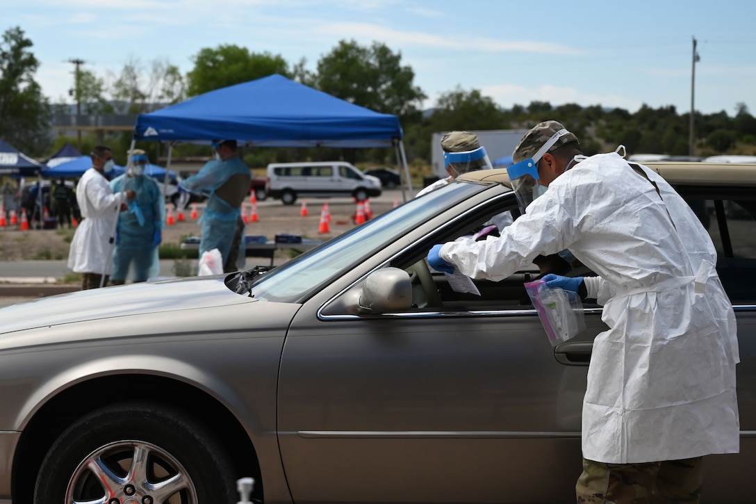 A man in a medical uniform looks inside a car.