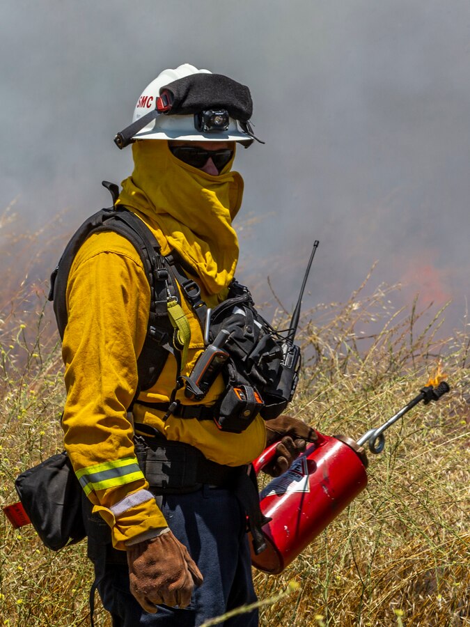 A firefighter with the Camp Pendleton Fire Department ignites vegetation with a drip torch during a controlled burn training as part of CPFD's Fire School on Marine Corps Base Camp Pendleton, California, June 3, 2020. The training is hosted by CPFD to strengthen partnerships with the surrounding agencies and to perform prescribed burns on the installation training areas in preparation for the upcoming fire season. (U.S. Marine Corps photo by Lance Cpl. Alison Dostie)
