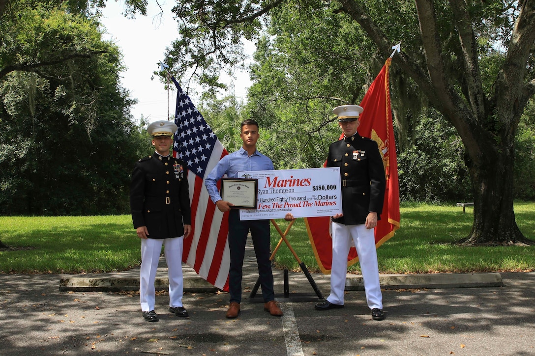 Lt. Col. Mark Lenzi, commanding officer, Recruiting Station Tampa, poses for a photo with Ryan Thompson, an Edgewater High School graduate, after receiving his Naval Reserve Officers Training Corps scholarship check, June 26, 2020, Tampa, Fla. Ryan emulates the fighting spirit that Marines have and was selected based off his overall character in his community and at home and has earned $180,000 in scholarship funds. Ryan is scheduled to attend Arizona State University in the fall. (Official Marine Corps photo by Sgt. Calvin Shamoon/ released)