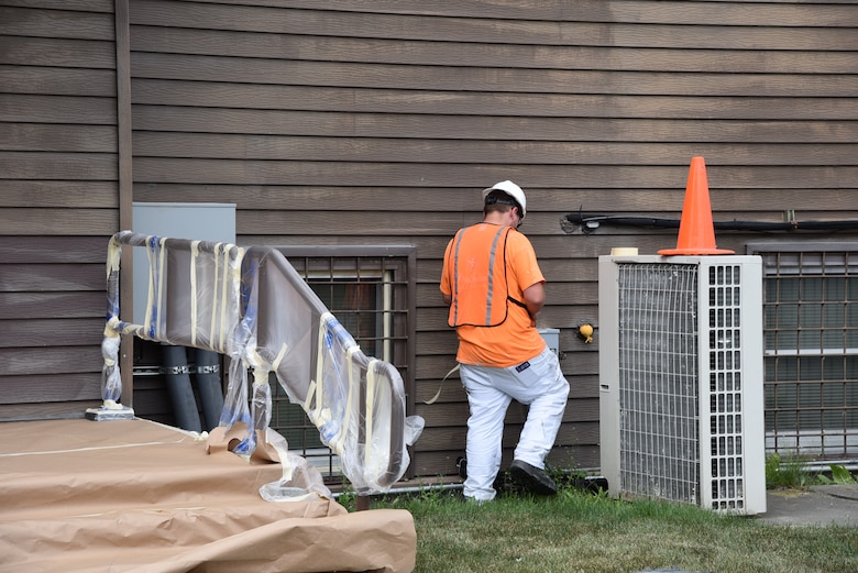 A worker tapes off equipment in preparation for painting the northeast side of the building.