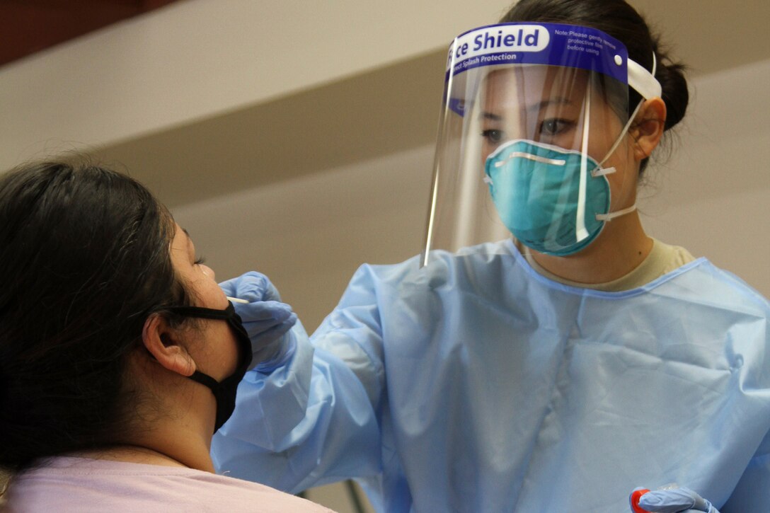 A guardsman in protective gear administers a COVID-19 test.