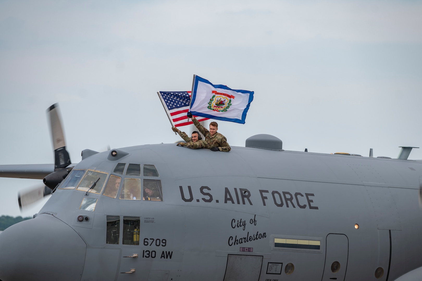 Airmen wave the United States and State of West Virginia Flags as they taxi onto the apron after returning from deployment on July 16, 2020 at McLaughlin Air National Guard Base, Charleston, W.Va. Approximately 50 Airmen returned in a two day span from Kuwait, where they provided support for C-130H operations in the Middle East Area of Responsibility. (U.S. Air National Guard Photo by Staff Sgt. Caleb Vance)