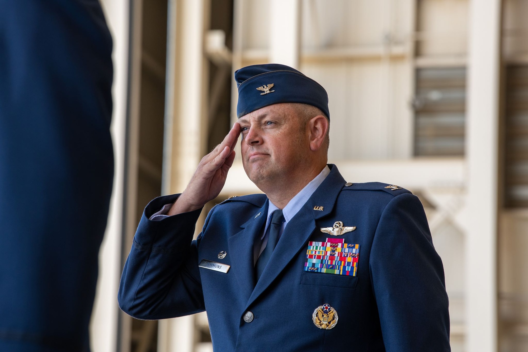 A man in dress uniform salutes. His face is determined.