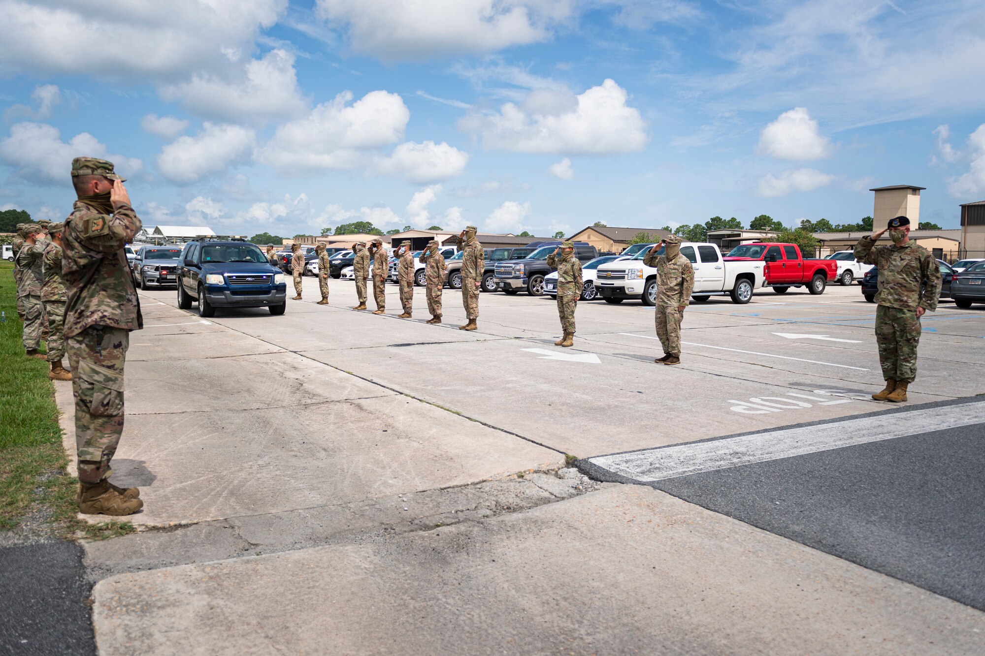 A photo of Airmen saluting a line of cars