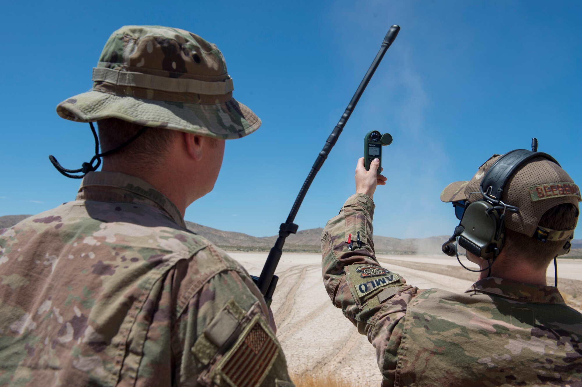 Maj. Clark Beesemyer, 621st Mobility Support Operations Squadron air mobility liaison officer, checks the wind speed and direction, while Capt. Eric Steen, 621st MSOS AMLO, stands by to report the information to a C-17 Globemaster III pilot prior to landing on a dirt runway July14, 2020 at Fort Irwin, Calif. AMLOs are comprised of pilots and navigators who are trained to help aircraft takeoff and land safely when there is no air traffic control tower present. (U.S. Air Force photo by Staff Sgt. Sarah Brice)