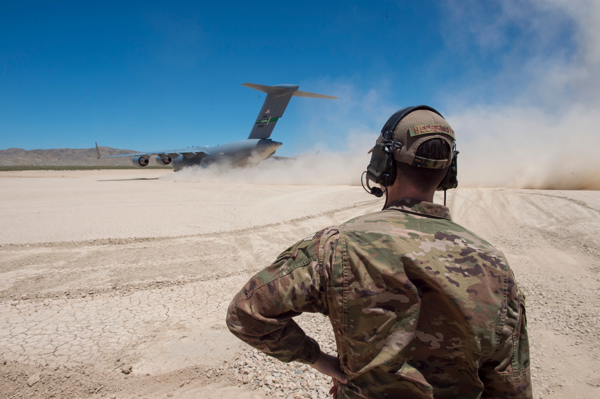 Maj. Clark Beesemyer, 621st Mobility Support Operations Squadron air mobility liaison officer, looks on as a C-17 Globemaster III taxis onto a ramp he helped land and direct to its destination July14, 2020 at Fort Irwin, Calif. AMLOs integrated with Army or Marine Corps personnel and spends most of their time with them conducting airfield operations. (U.S. Air Force photo by Staff Sgt. Sarah Brice)