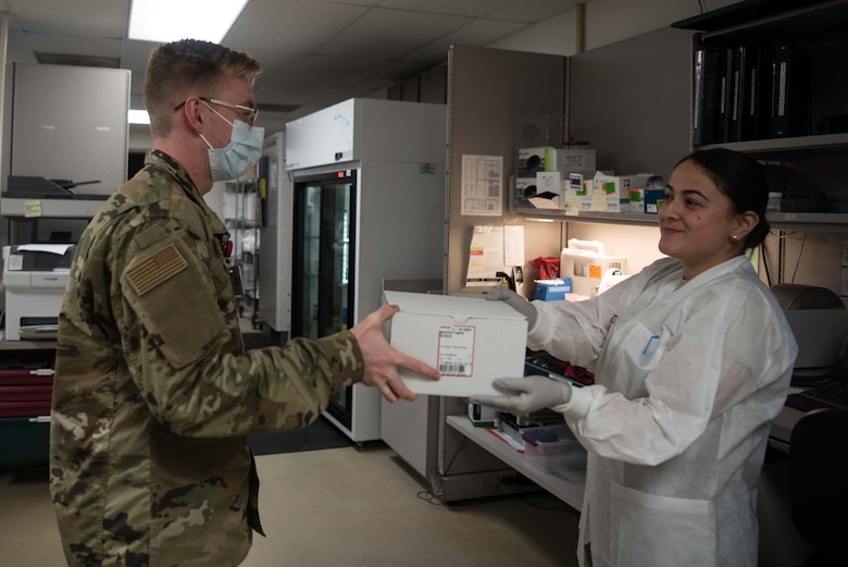 Airman 1st Class Bailey Pitcher, 22nd Medical Support Squadron acquisitions technician, delivers a package to Senior Airman Leidy Ruiz, 22nd MDSS lab technician, July 15, 2020, at McConnell Air Force Base, Kansas. The medical material Airmen support the mission by building first aid kits for flight crews on McConnell’s KC-135 Stratotanker and the KC-46A Pegasus aircraft. (U.S. Air Force photo by Senior Airman Alexi Bosarge)