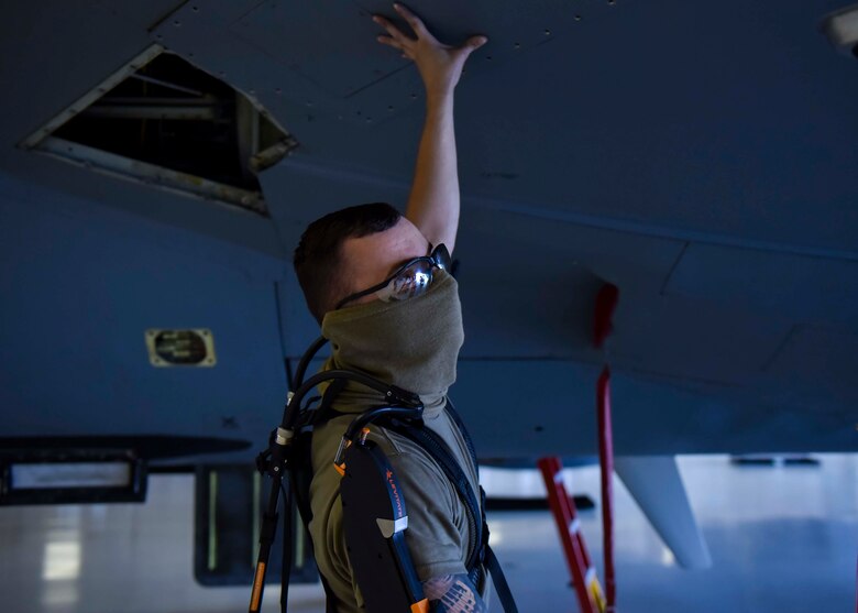 Senior Airman Reid Carter, 92nd Maintenance Squadron crew chief, holds a panel from a KC-135 Stratotanker while wearing an exoskeleton apparatus at Fairchild Air Force Base, Washington, July 17, 2020. The apparatus is designed to help Airmen work above their heads comfortably and with ease. (U.S. Air Force photo by Airman 1st Class Kiaundra Miller)