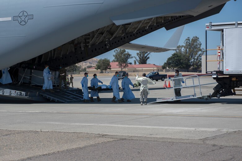 U.S. Air Force Airmen from the 775th Expeditionary Aeromedical Evacuation Flight offload a COVID-19 positive patient from a C-17 Globemaster III July 17, 2020 at Travis Air Force Base, California. Travis Airmen transported the patient from the Indo-Pacific Command area of responsibility as part of the Air Force's response to the COVID-19 outbreak. This transport marked the Air Force's first TIS mission into the INDOPACOM AOR and the 18th time employing TIS units to transport COVID-19-positive passengers. (U.S. Air Force photo by Airman 1st Class Cameron Otte)