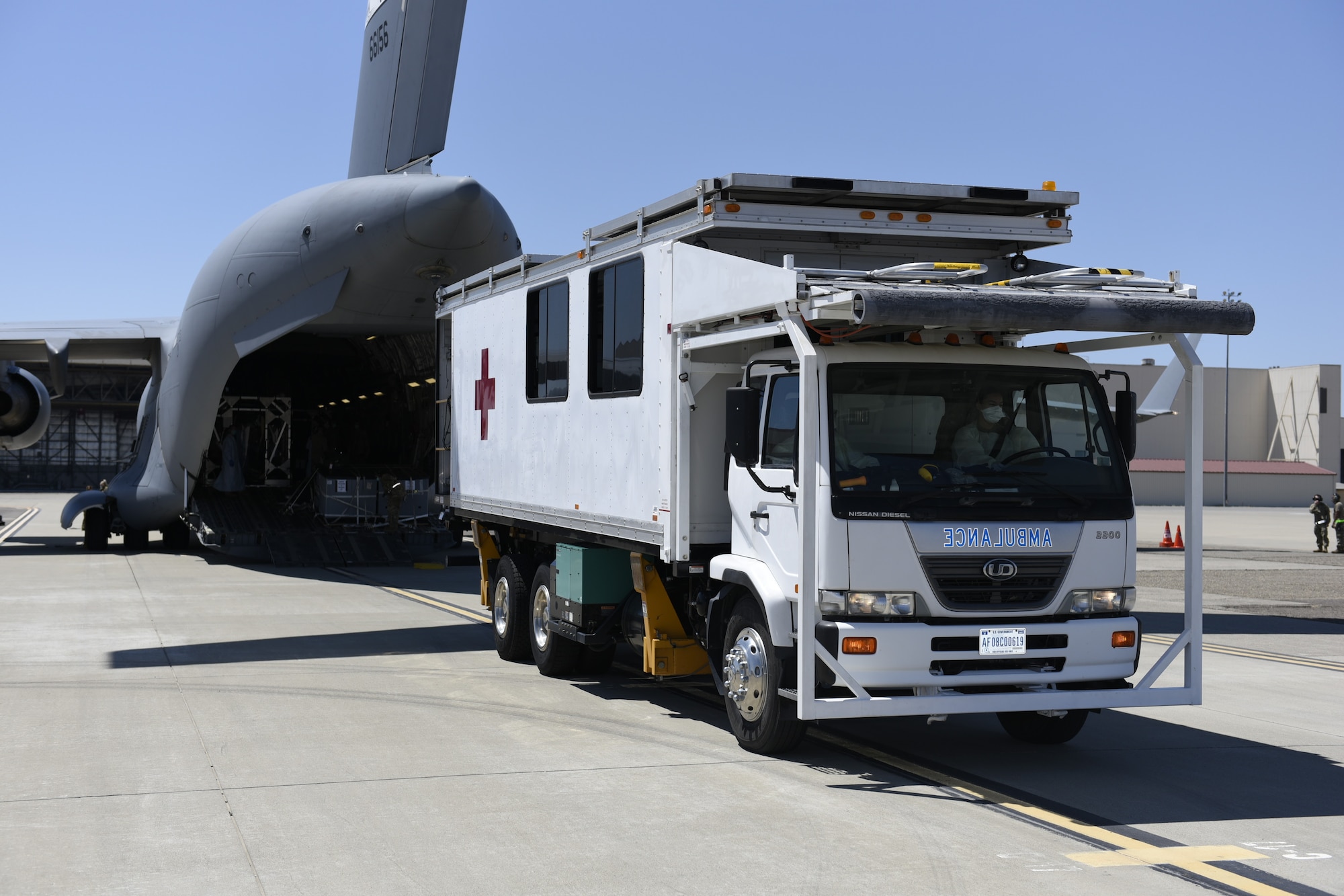 U.S. Air Force Airmen with the 60th Aerospace Medicine Squadron back up a high deck patient loading platform to a C-17 Globemaster III for an incoming COVID-19-positive patient July 17, 2020 at Travis Air Force Base, California. Travis Airmen transported the patient from the Indo-Pacific Command area of responsibility as part of the Air Force’s response to the COVID-19 outbreak. This transport marked the Air Force’s first TIS mission into the INDOPACOM AOR and the 18th time employing TIS units to transport COVID-19 positive passengers. (U.S. Air Force photo by Airman 1st Class Cameron Otte)