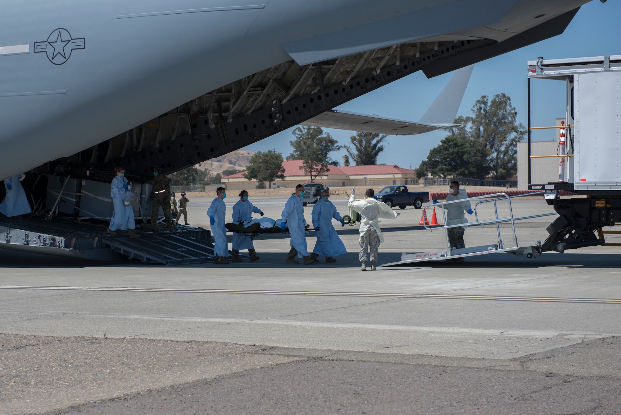 U.S. Air Force Airmen from the 775th Expeditionary Aeromedical Evacuation Flight offload a COVID-19 positive patient from a C-17 Globemaster III at Travis Air Force Base, California, July 17, 2020. Travis Airmen transported the patient from the Indo-Pacific Command area of responsibility as part of the Air Force’s response to the COVID-19 pandemic. This transport marked the Air Force’s first TIS mission into the INDOPACOM AOR, and the 18th time employing TIS units to transport COVID-19-positive passengers. (U.S. Air Force photo by Airman 1st Class Cameron Otte)