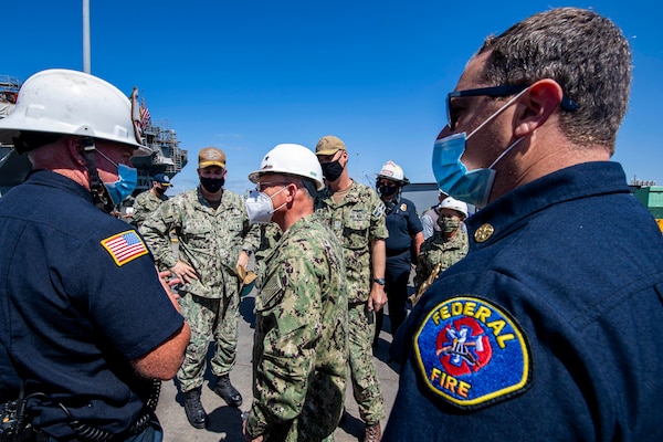 The Chief of Naval Operations (CNO) Adm. Mike Gilday speaks with federal firefighters on the pier next to the amphibious assault ship USS Bonhomme Richard (LHD 6).