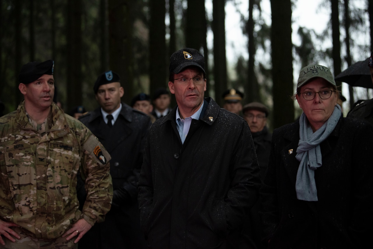 Man, woman look upon World War II battlefield. Military men in uniform are in the background.