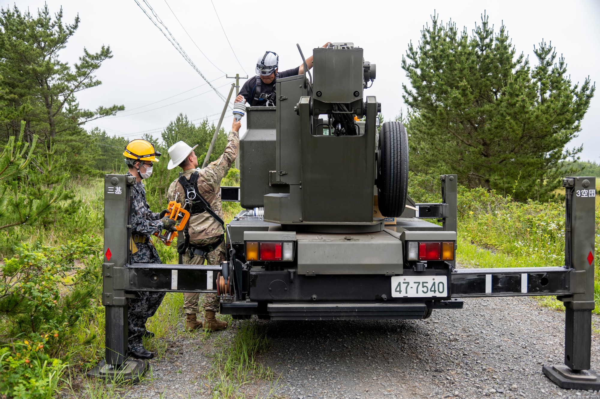 The 35th Civil Engineer Squadron and Japan Air Self-Defense Force Airmen equivalent, work together to replace deteriorating high voltage overhead lines at Draughon Range in Misawa, Japan, July 15.