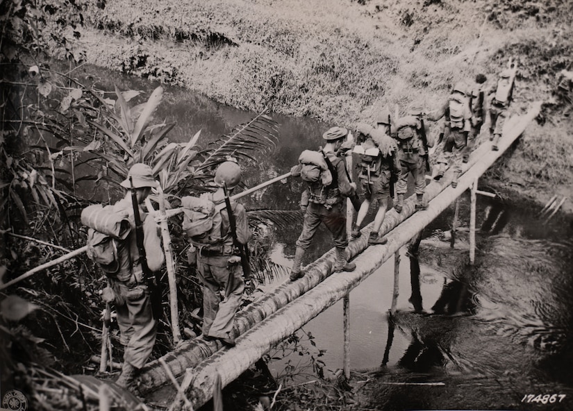Soldiers with Company L, 3rd Battalion, 128th Infantry, 32nd Division, cross a creek between Warisota Plantation and Borio, New Guinea, Nov. 17, 1942.