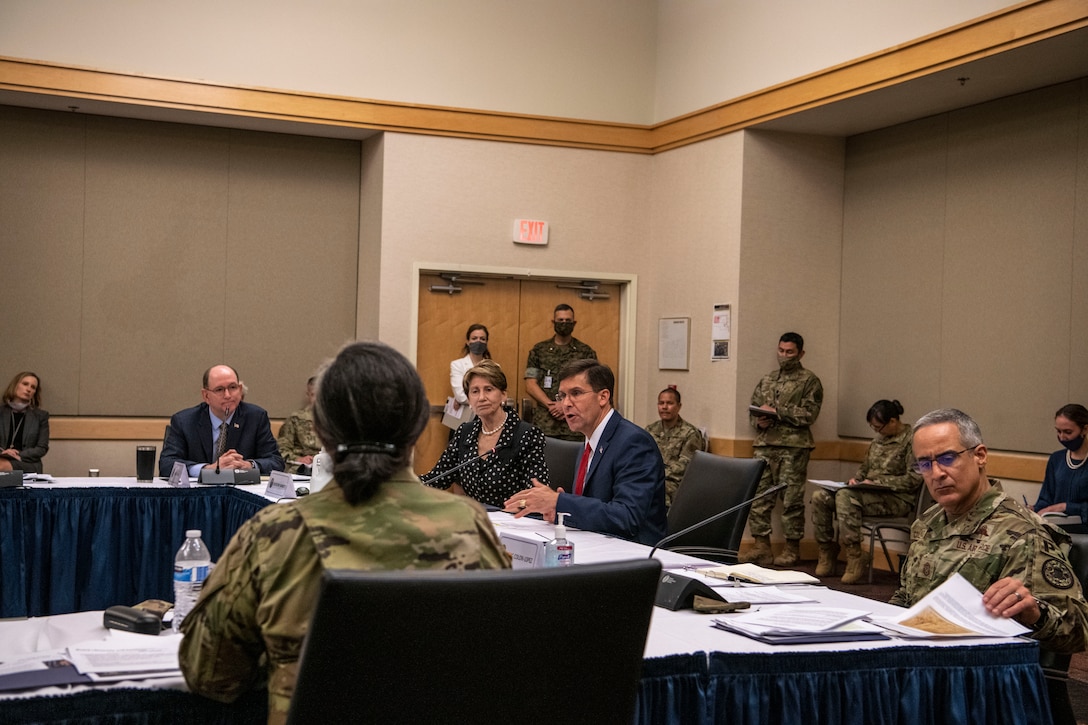 Service members and civilians sit around a large table.