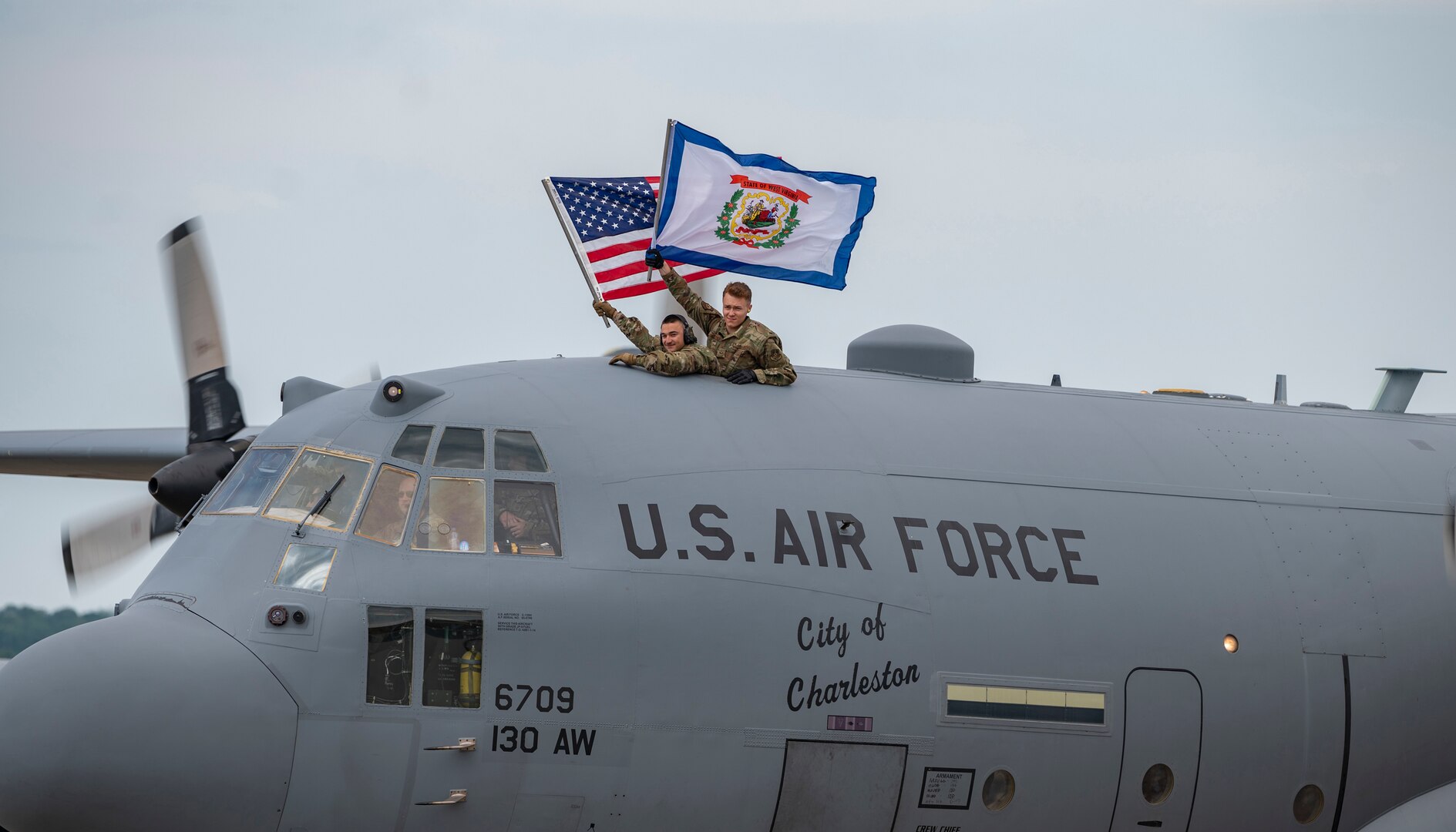 West Virginia National Guard Airmen wave the U.S. and West Virginia flags as they taxi onto the apron after returning from deployment on July 16, 2020, at McLaughlin Air National Guard Base, Charleston, W.Va. Approximately 50 Airmen returned over two days from Kuwait, where they provided support for C-130H operations in the Middle East area of responsibility.