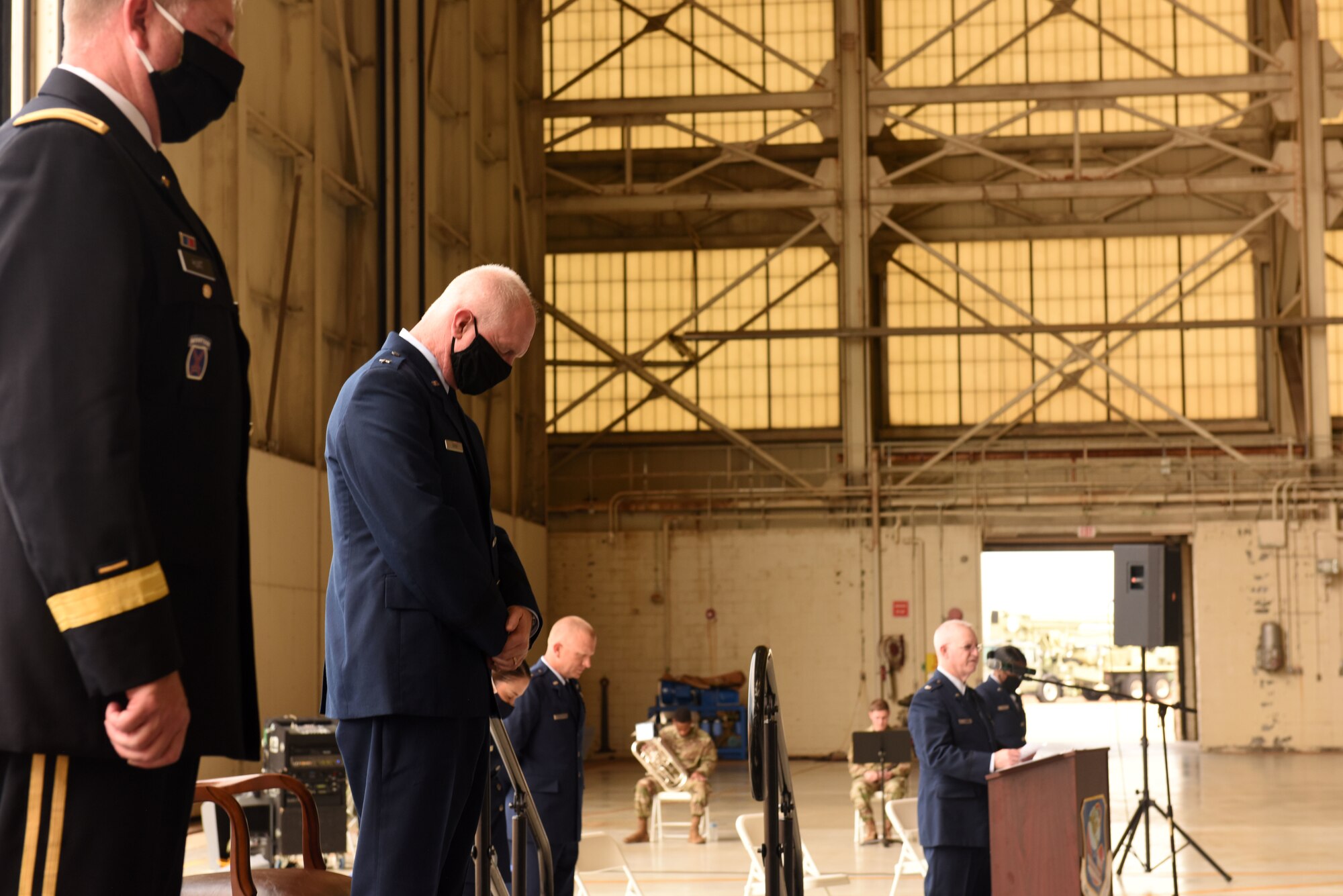 U.S. Air Force Chaplain, Lt. Col. Jeffrey Kidd (right), gives a closing prayer during the promotion ceremony of U.S. Air Force Brig. Gen. Allan R. Cecil (center), North Carolina National Guard Chief of Staff, held at the North Carolina Air National Guard Base, Charlotte Douglas International Airport, July 18, 2020. Family, friends, and guard members gather to watch Col. Cecil pin on the rank of Brigadier General.