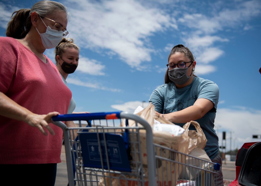 Members of the Kirtland Spouses Club receive donation items.