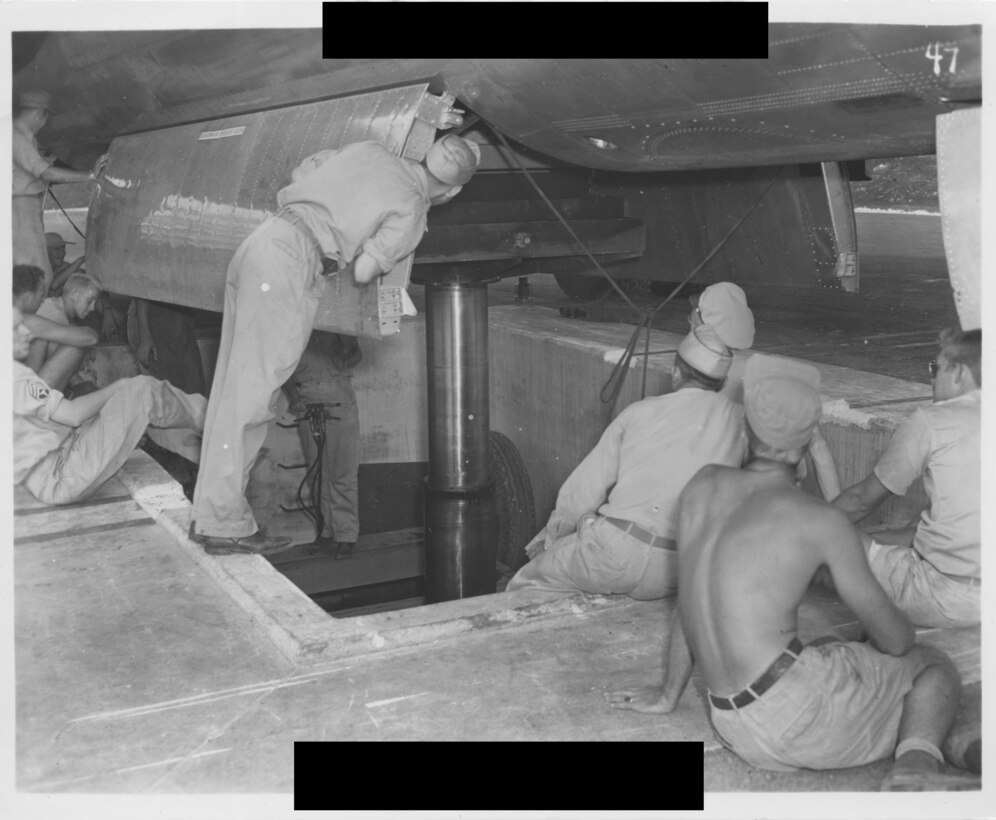 Several men look into the belly of an open airplane.