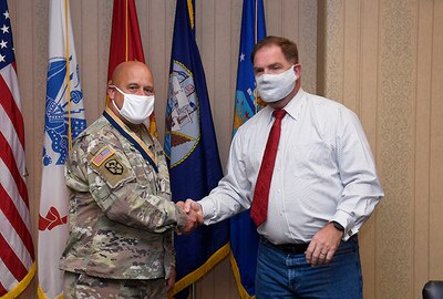 Col. Bondy and DLA Disposition Services Director Mike Cannon shake hands while both wear mask.