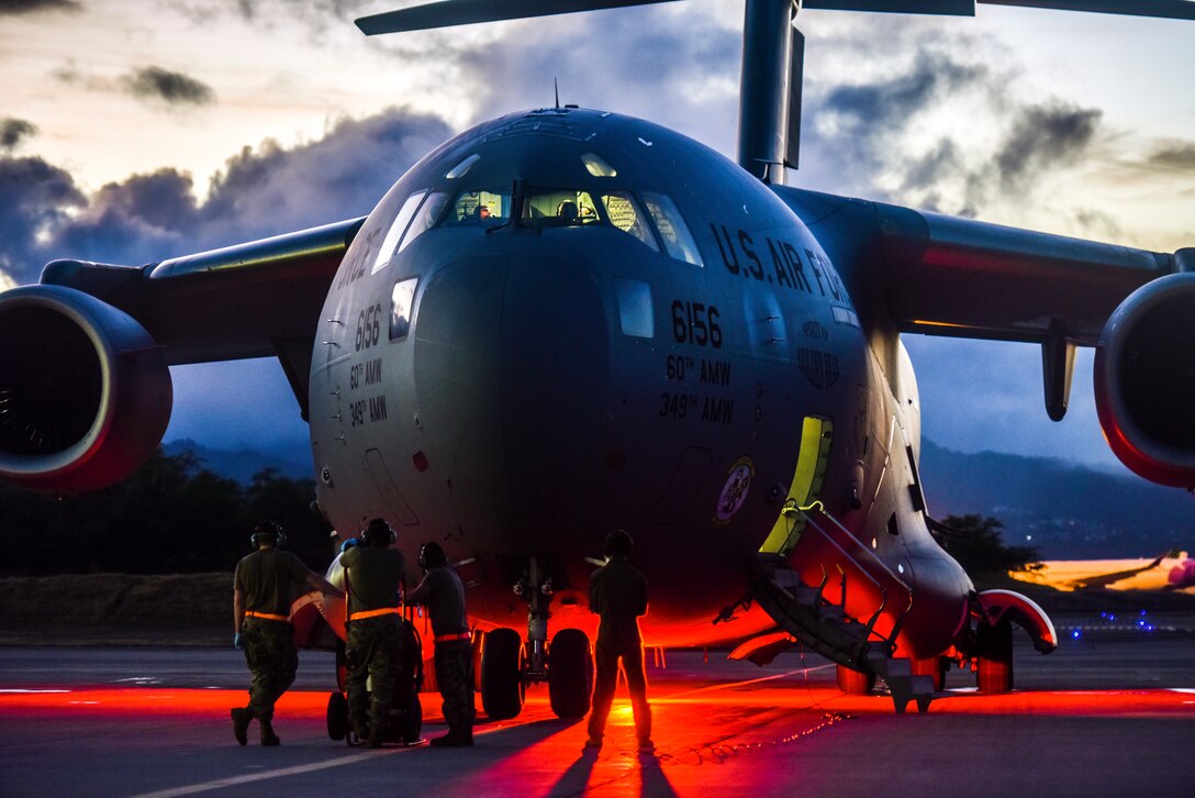 Airmen stand near an aircraft.