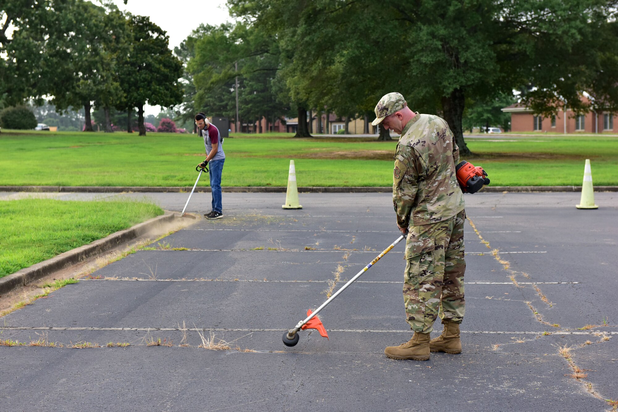 Airman with weedeater cleaning up parking lot