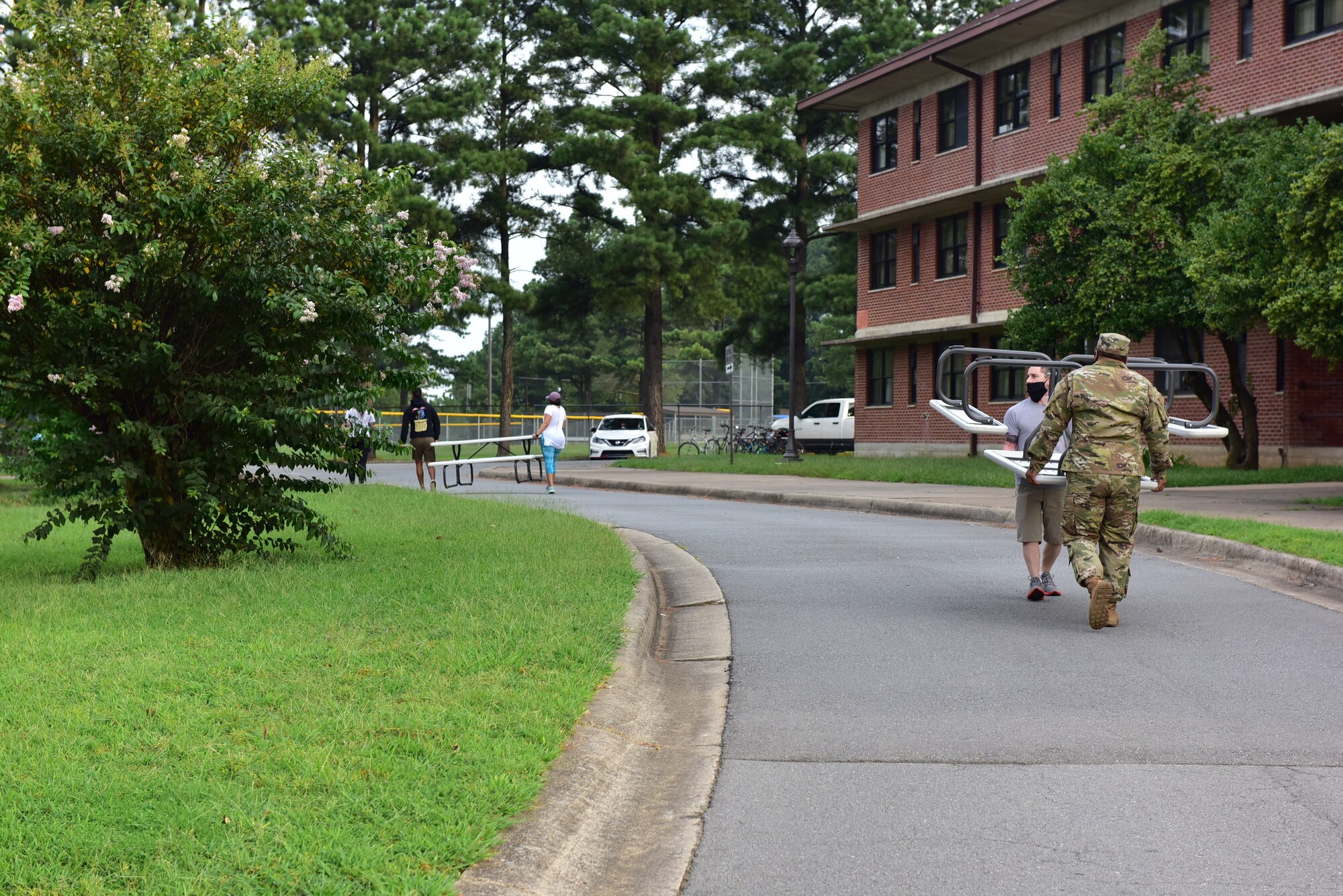Airmen carrying aluminum table past Dorm