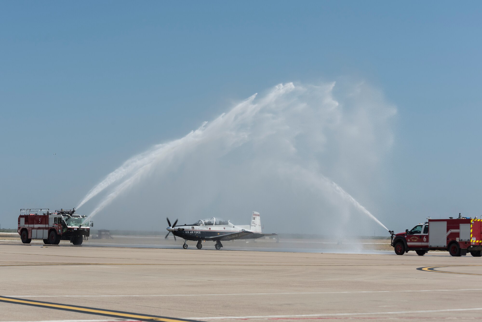 Col. Lee Gentile, 47th Flying Training Wing commander, ends his fini flight by taxiing under the arch of water, July 17, 2020 at Laughlin Air Force Base Texas. He parked in front of the base operations building where he was greeted by family, friends and co-workers to celebrate his last flight as an Air Force officer. (U.S. Air Force photo by Senior Airman Anne McCready)
