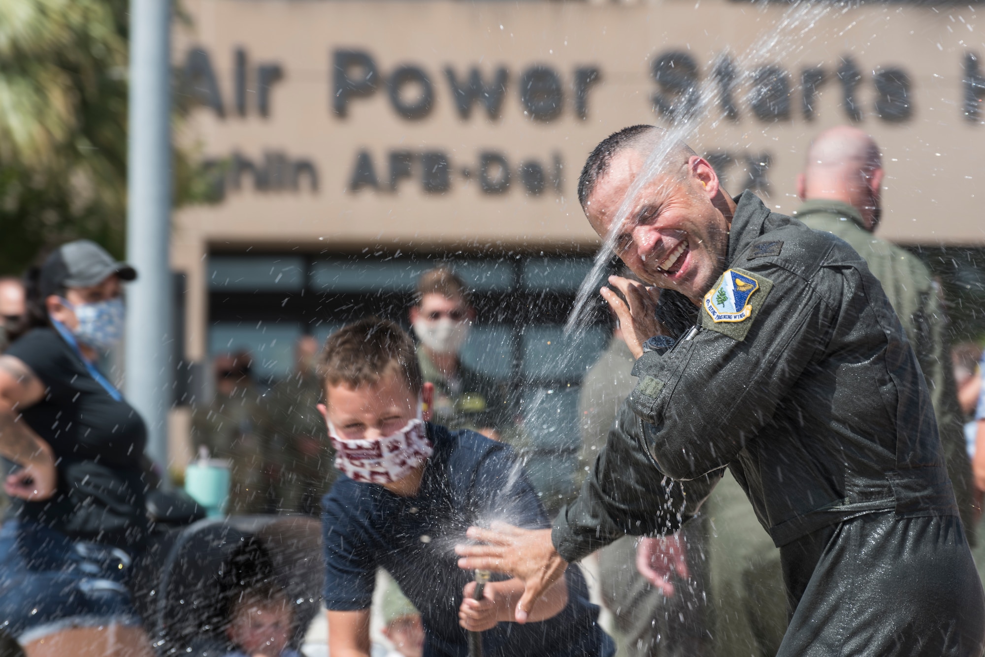 Col. Lee Gentile, 47th Flying Training Wing commander, is doused with water by his son, July 17, 2020 at Laughlin Air Force Base Texas. In celebration of a pilot’s fini flight, it is tradition for his family to shower the pilot with water and champagne. (U.S. Air Force photo by Senior Airman Anne McCready)