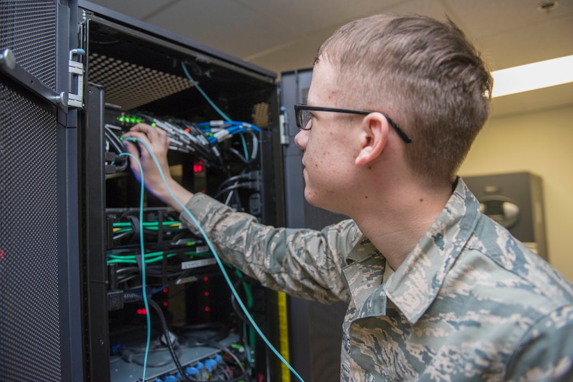 A young service member works on some information technology components.