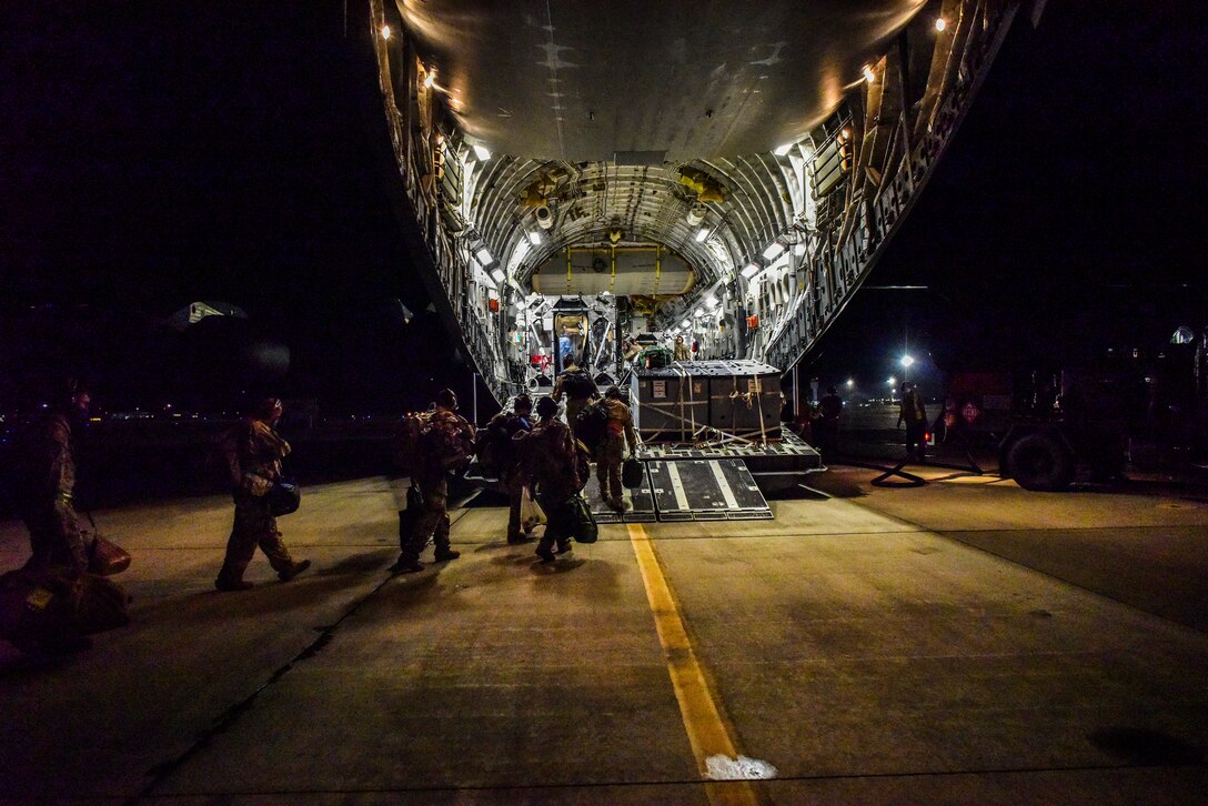 Airmen walk in line to enter an aircraft.