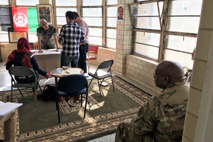 A group of people stand around a table.