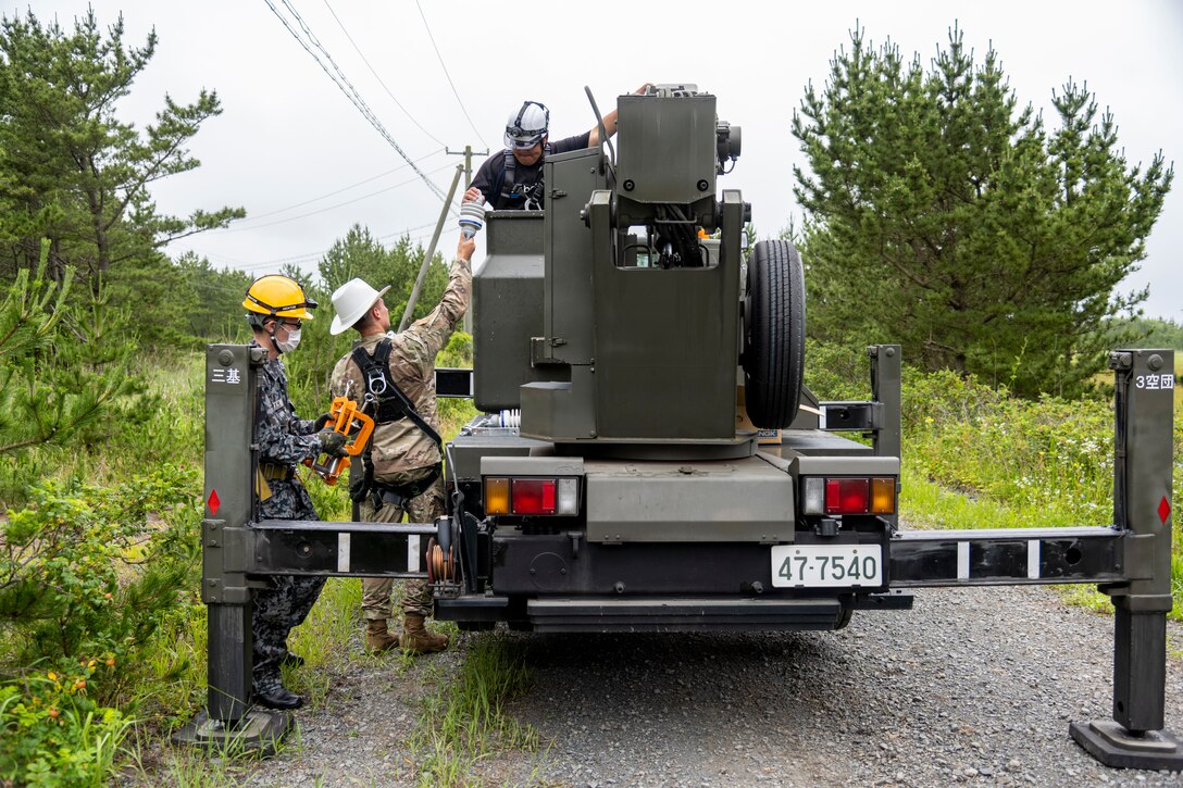The 35th Civil Engineer Squadron and Japan Air Self-Defense Force Airmen equivalent, work together to replace deteriorating high voltage overhead lines at Draughon Range in Misawa, Japan, July 15.
