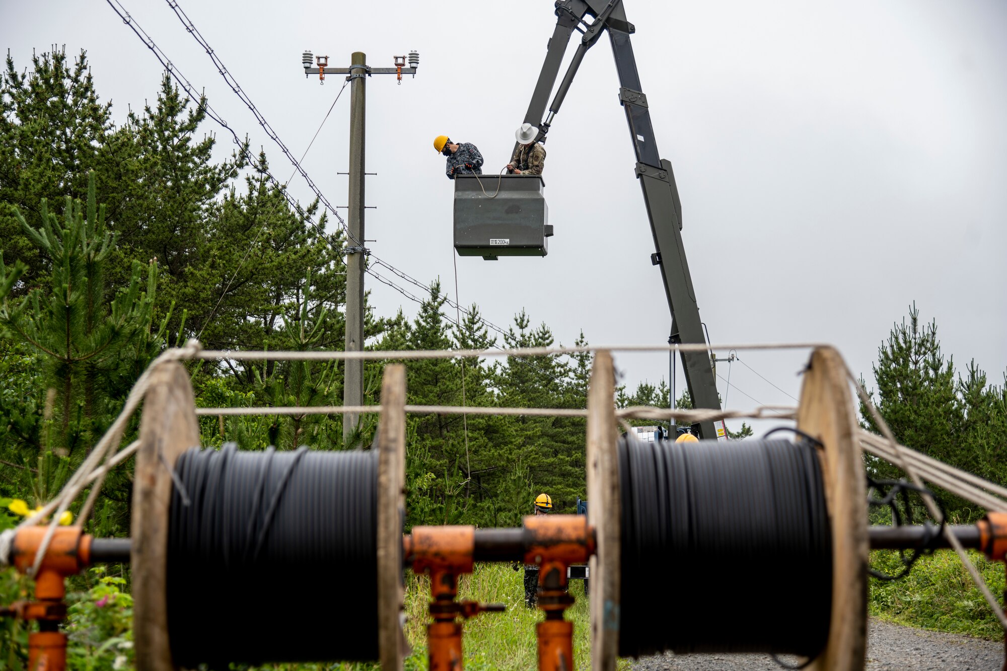 The 35th Civil Engineer Squadron and Japan Air Self-Defense Force Airmen equivalent, work together to replace deteriorating high voltage overhead lines at Draughon Range in Misawa, Japan, July 15.