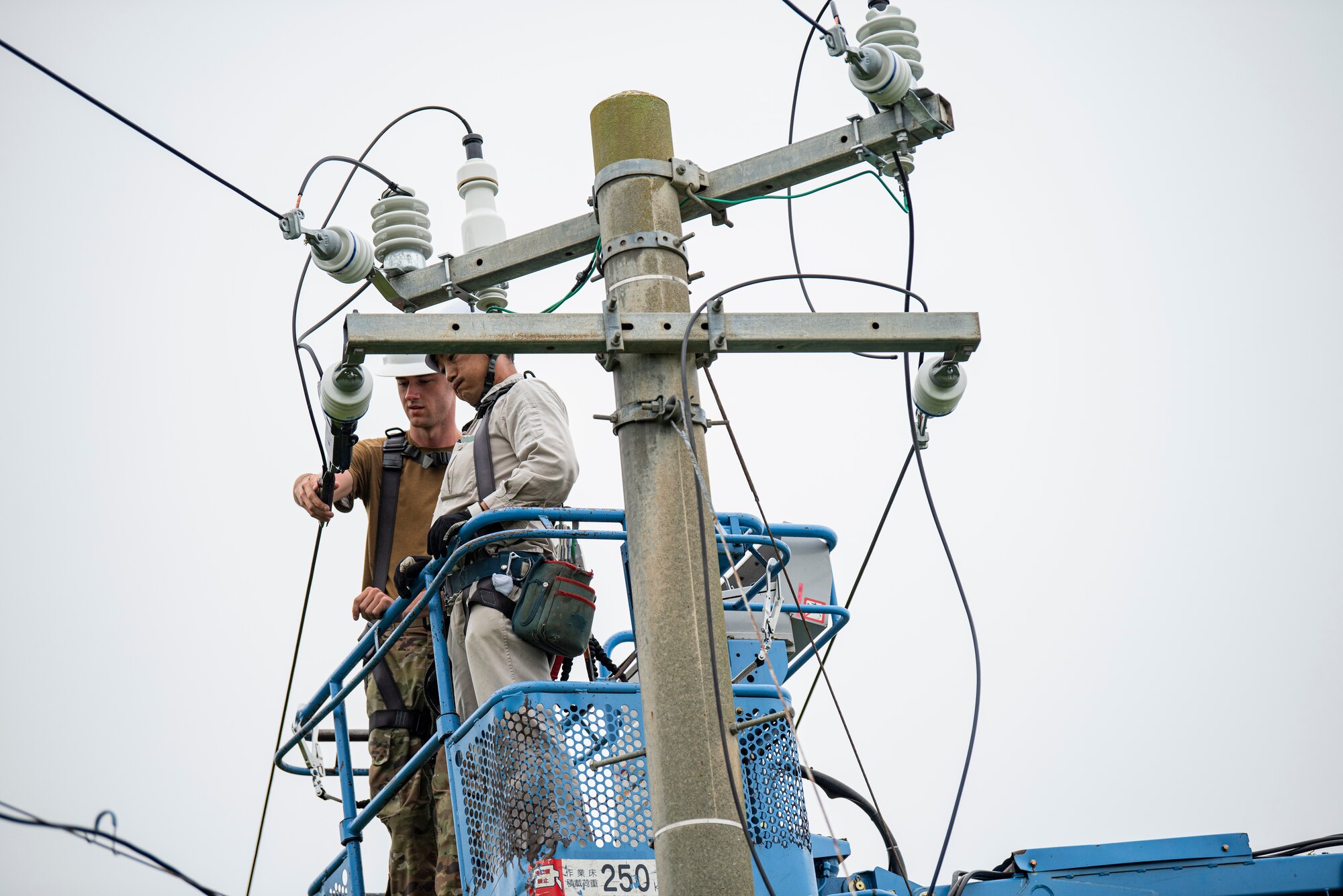 The 35th Civil Engineer Squadron and Japan Air Self-Defense Force Airmen equivalent, work together to replace deteriorating high voltage overhead lines at Draughon Range in Misawa, Japan, July 15.