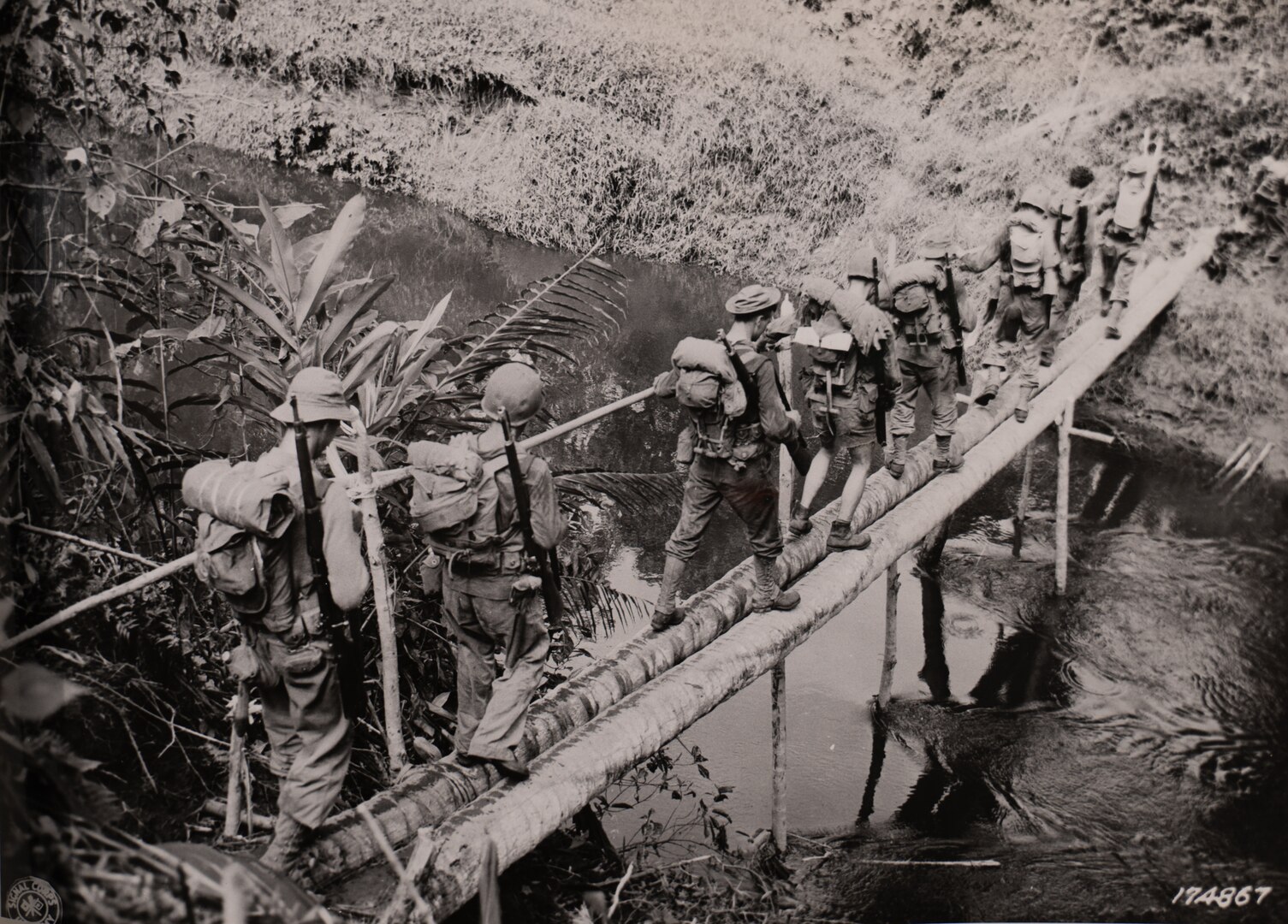 Soldiers with Company L, 3rd Battalion, 128th Infantry, 32nd Division, cross a creek between Warisota Plantation and Borio, New Guinea, Nov. 17, 1942.