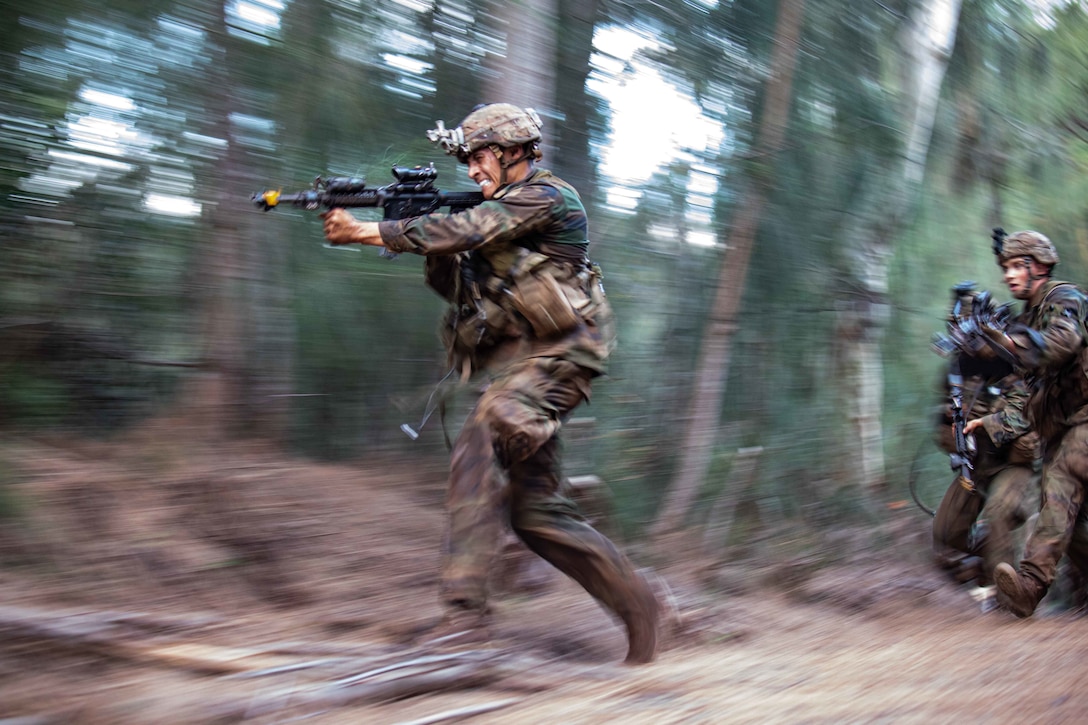 A soldier runs while aiming his gun,