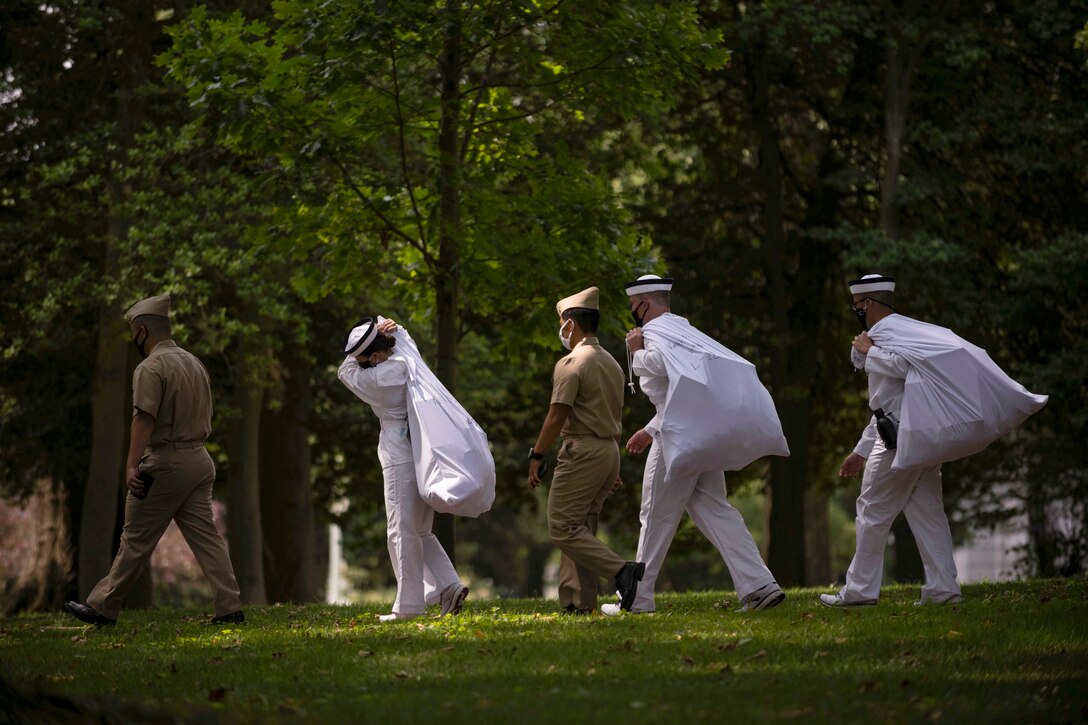 Midshipmen walk together in a forest-like area.