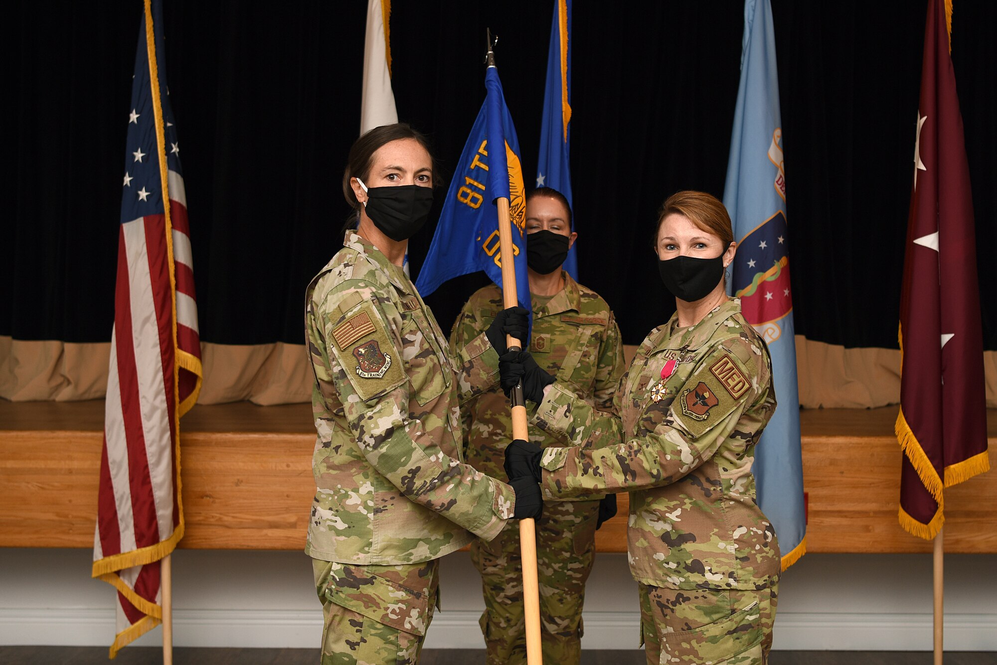 U.S. Air Force Col. Heather Blackwell, 81st Training Wing commander, takes the 81st Medical Group guidon from Col. Beatrice Dolihite, outgoing 81st MDG commander, during the 81st MDG change of command ceremony inside the Don Wiley Auditorium at Keesler Air Force Base, Mississippi, July 21, 2020. The passing of the guidon is a ceremonial symbol of exchanging command from on commander to another.. (U.S. Air Force photo by Senior Airman Suzie Plotnikov)