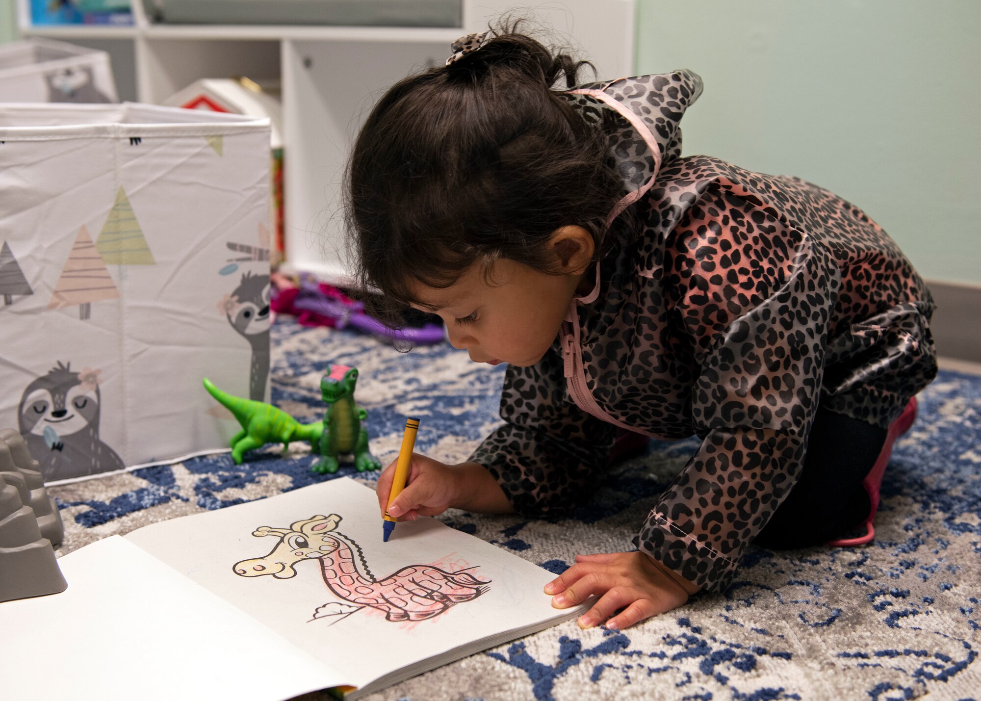Photo of a child drawing in a coloring book in a room.