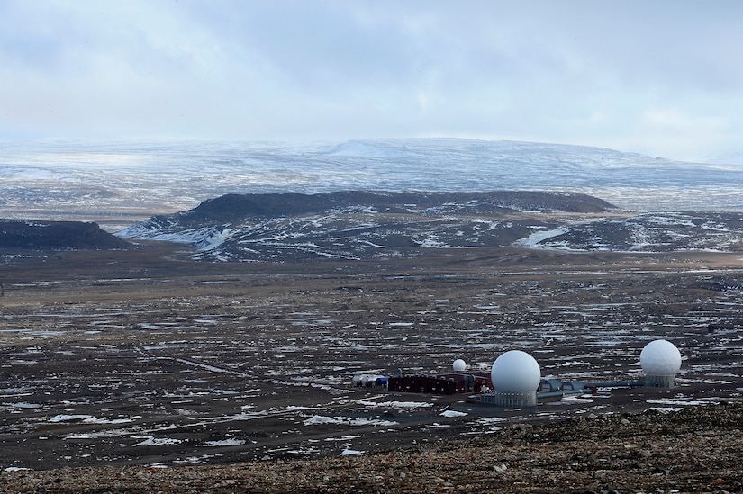 Golf-ball-like radar domes sit on a rocky, snowy landscape.