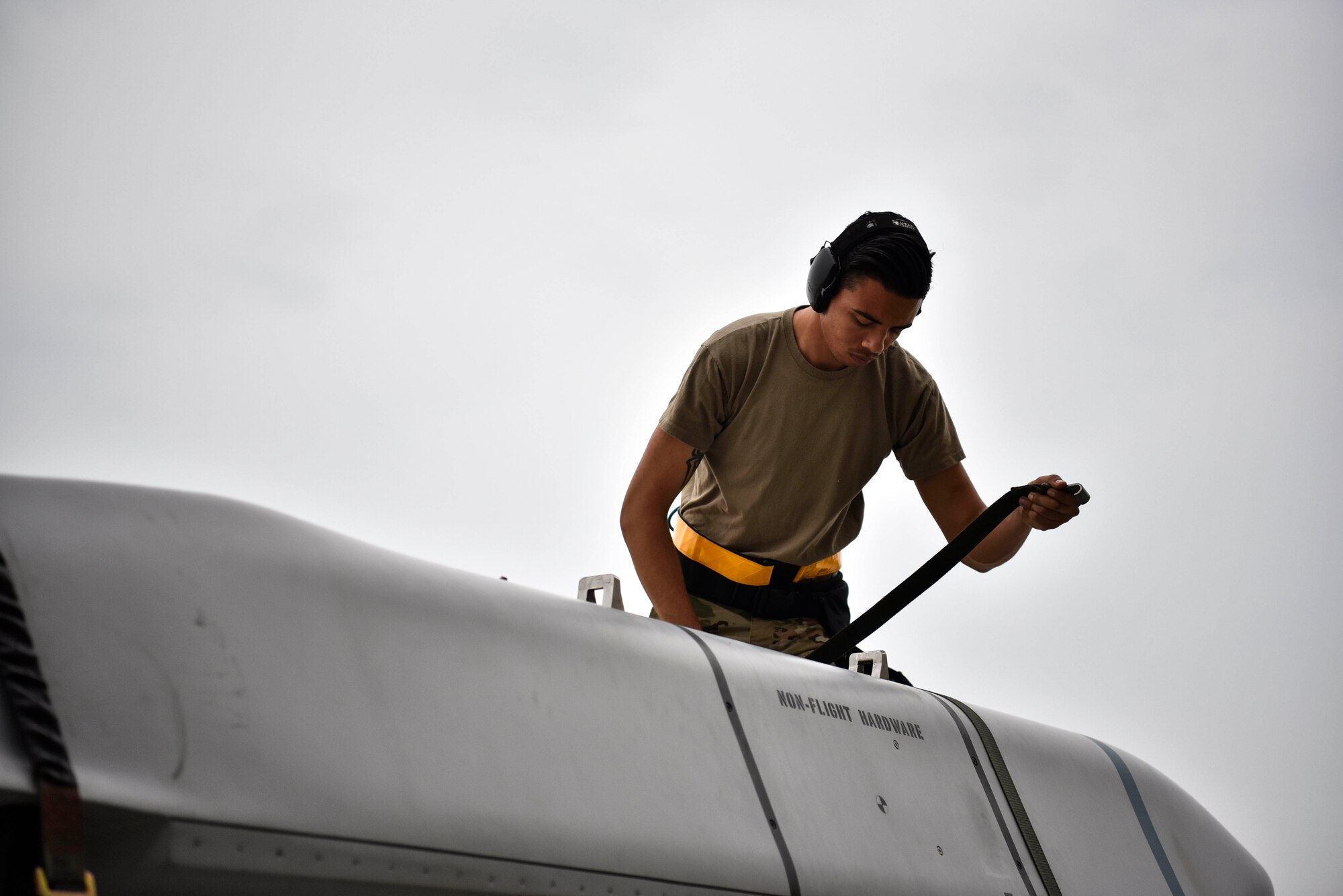 A photo of an Airman unstrapping an inert missile.