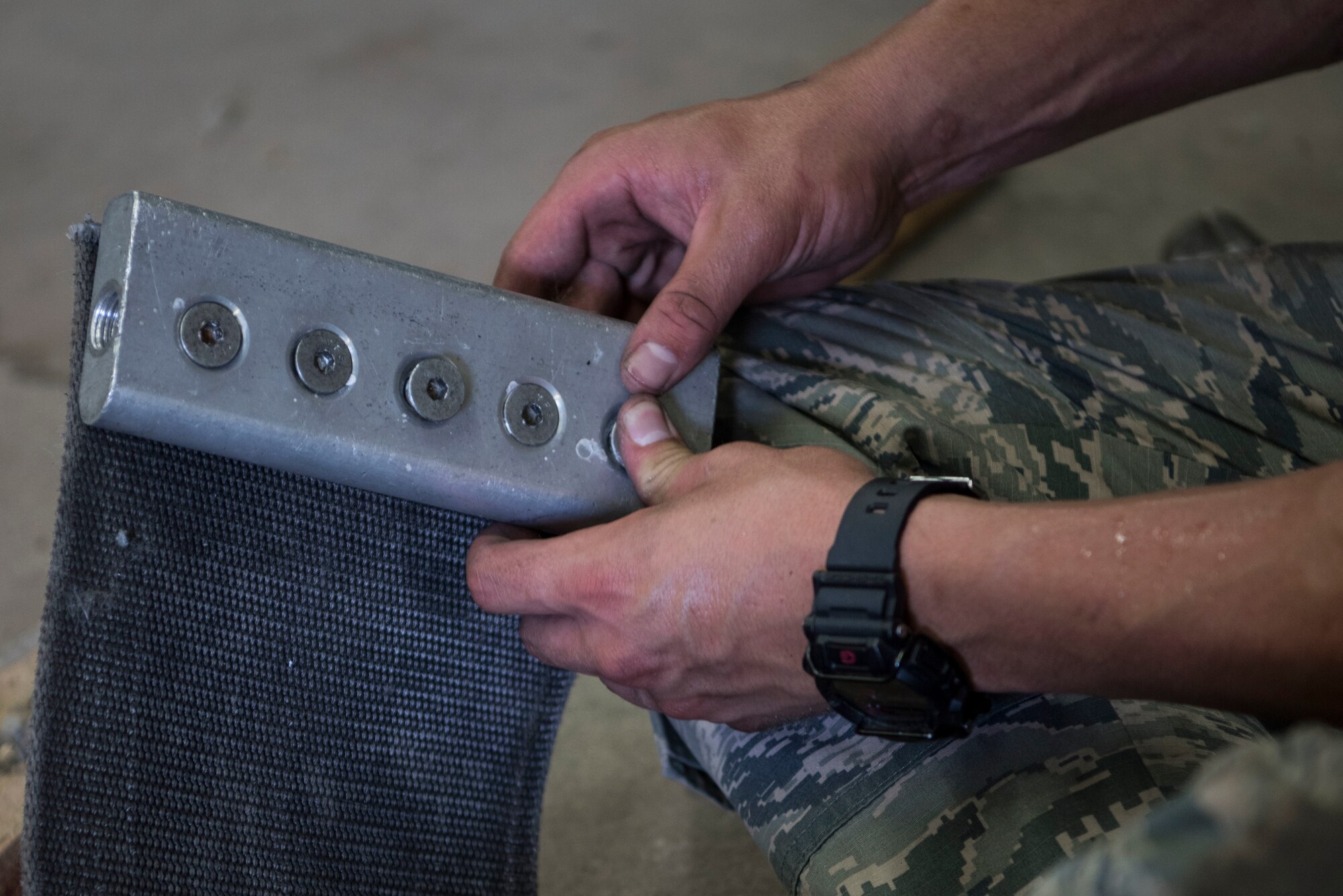 A U.S. Air Force Airman installs a clamp on a mobile aircraft arresting system shock absorber during Silver Flag.